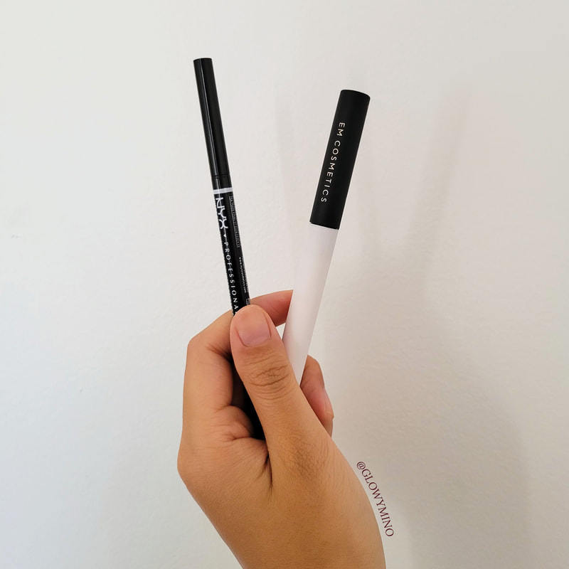 Holding my favorite brow products in front of a white wall: the NYX Micro Brow Pencil in Black and the Em Cosmetics Micro-Fluff Sculpting Brow Cream in Soft Ebony